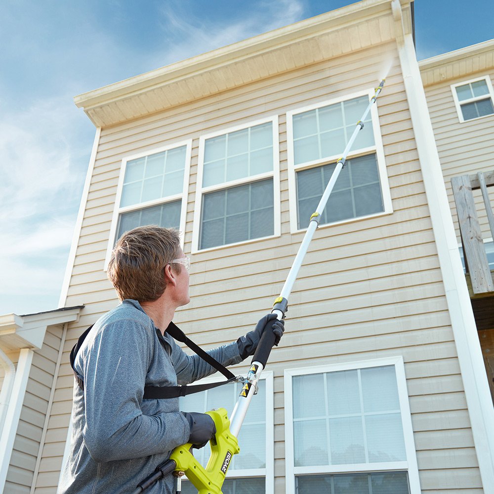 Technician carefully cleaning vinyl siding with low-pressure house washing equipment