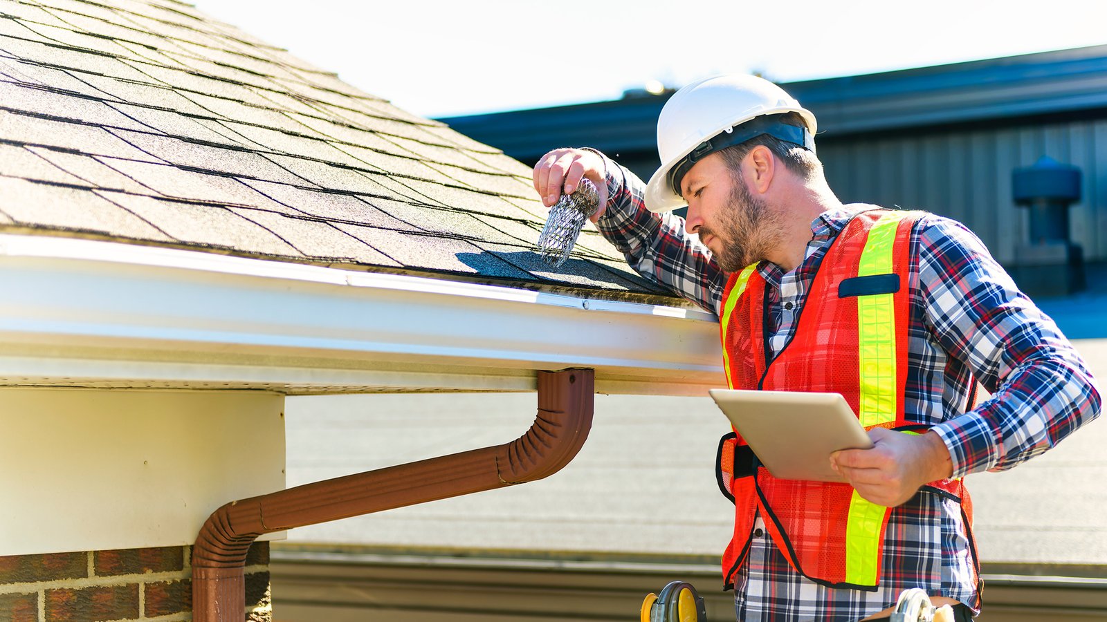 Roof professional examining flashing, vents, and shingles with a documented inspection checklist