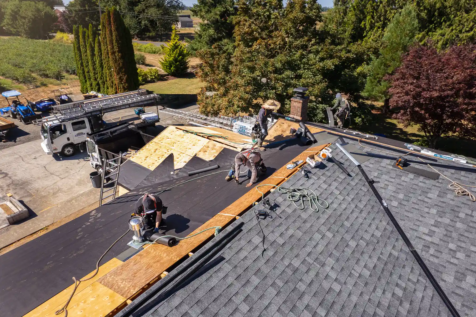 Crew replacing worn shingles on a single-story home in an active retirement neighborhood