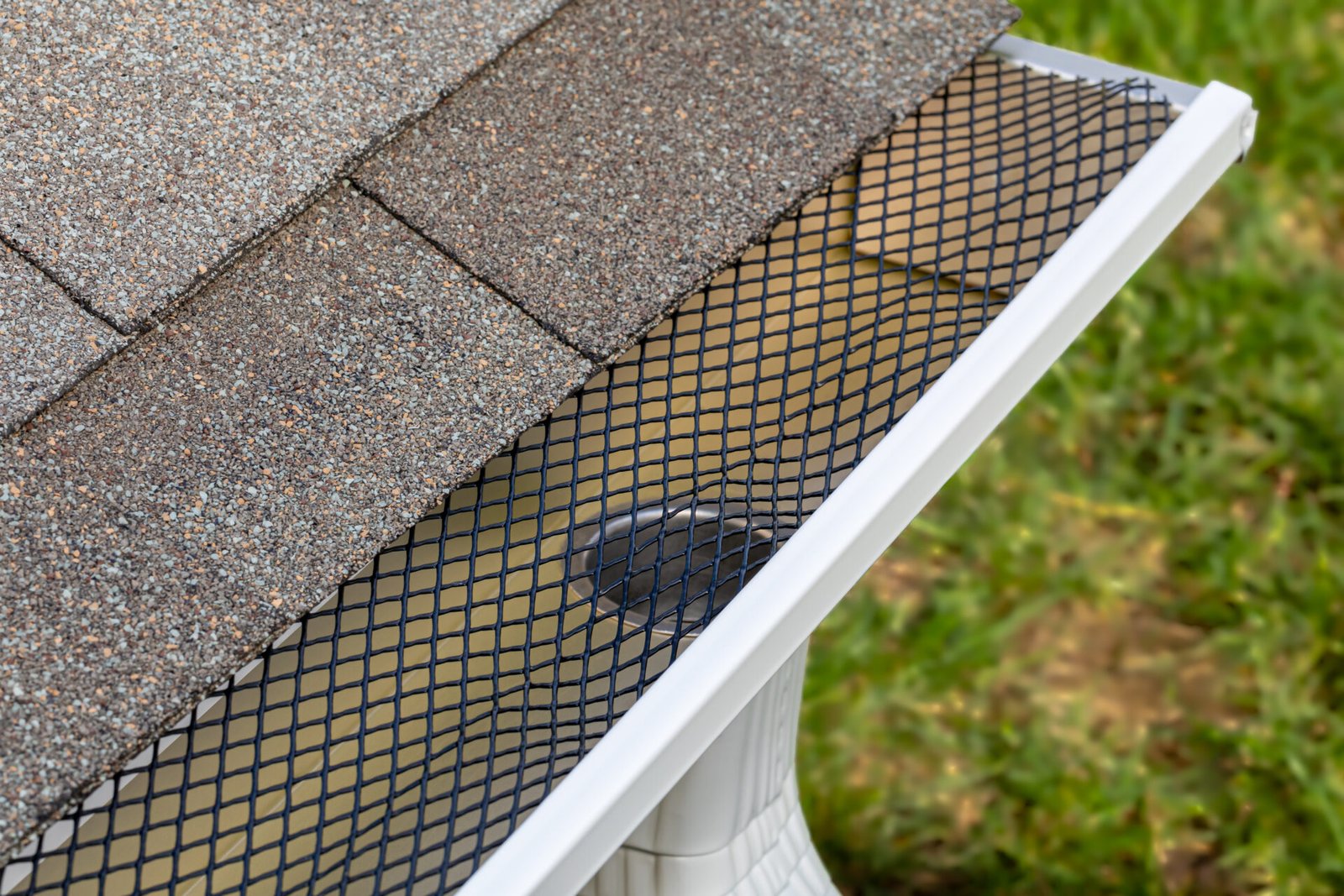 New gutter guards installed along a residential roofline above landscaped garden beds