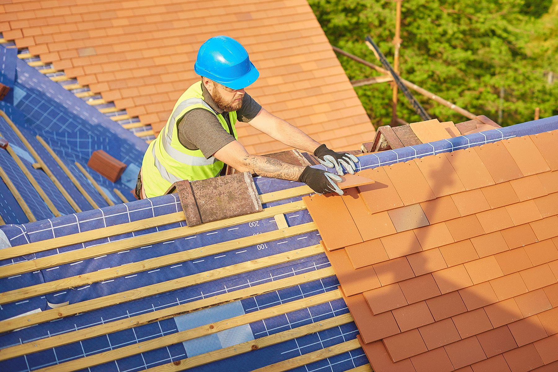 Experienced roofer inspecting roof edges, vents, and drainage areas during scheduled maintenance