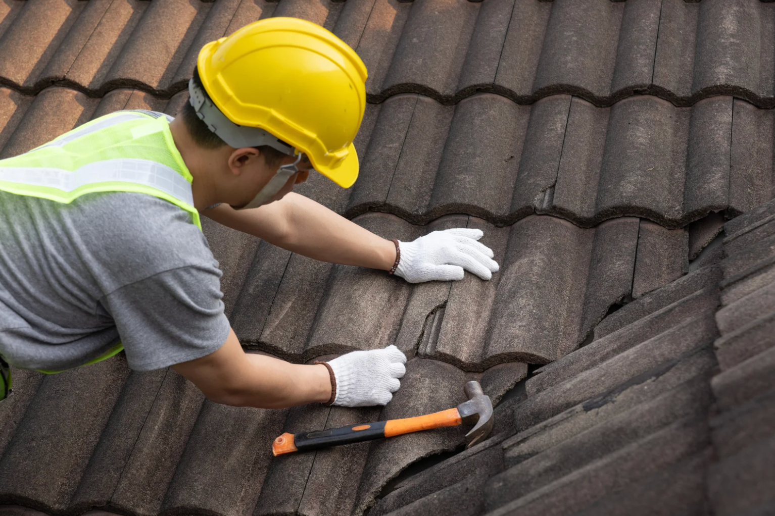 Experienced roofer inspecting storm-damaged shingles and flashing for immediate repair needs