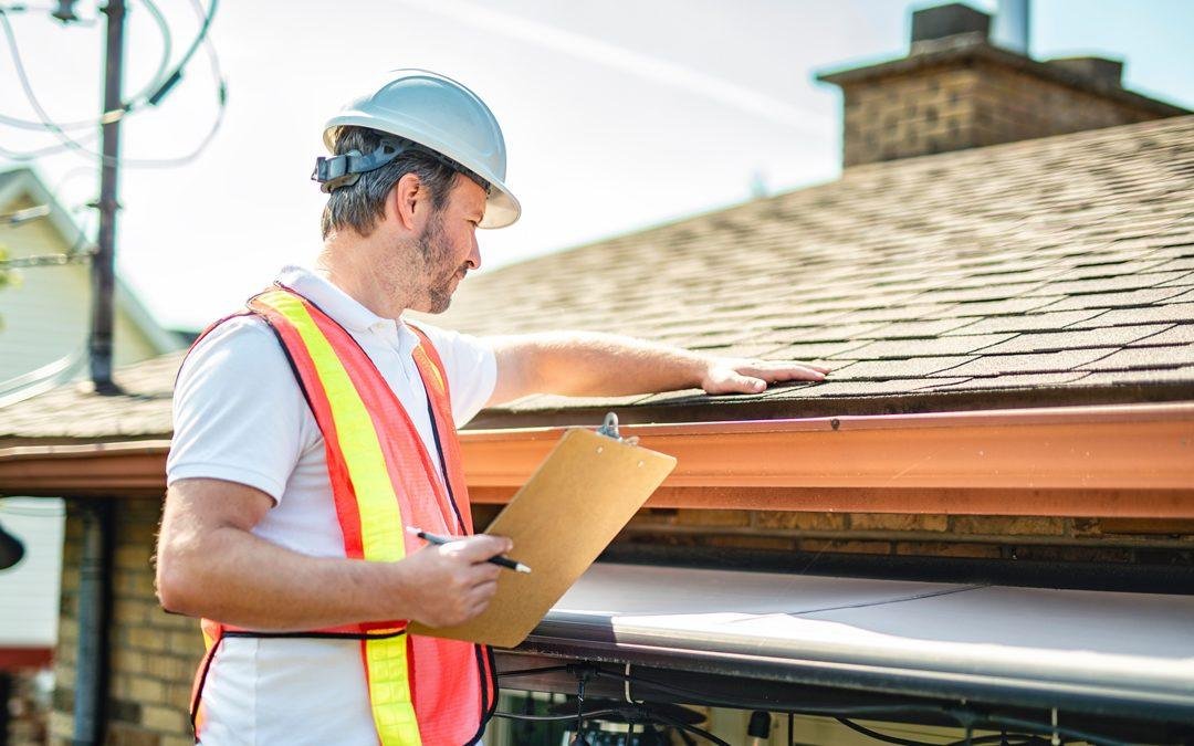 Inspector documenting shingle wear and flashing condition on a resale home roof