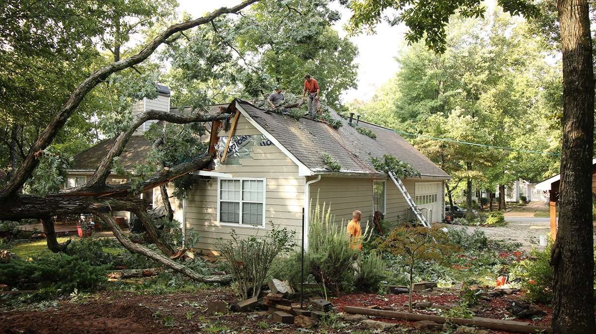 Experienced roofer inspecting wind-lifted shingles and damaged flashing after a Florida storm