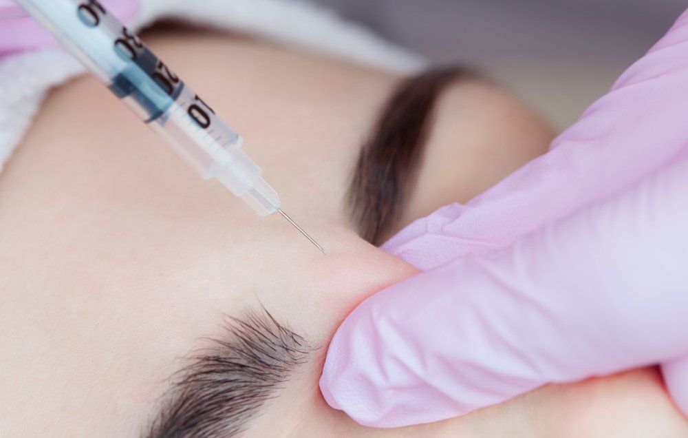 Client receiving a facial assessment before injectable treatment in a calm studio setting